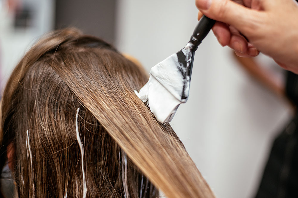EIn Pinsel, der Färbepaste auf eine Haarsträhne aufträgt