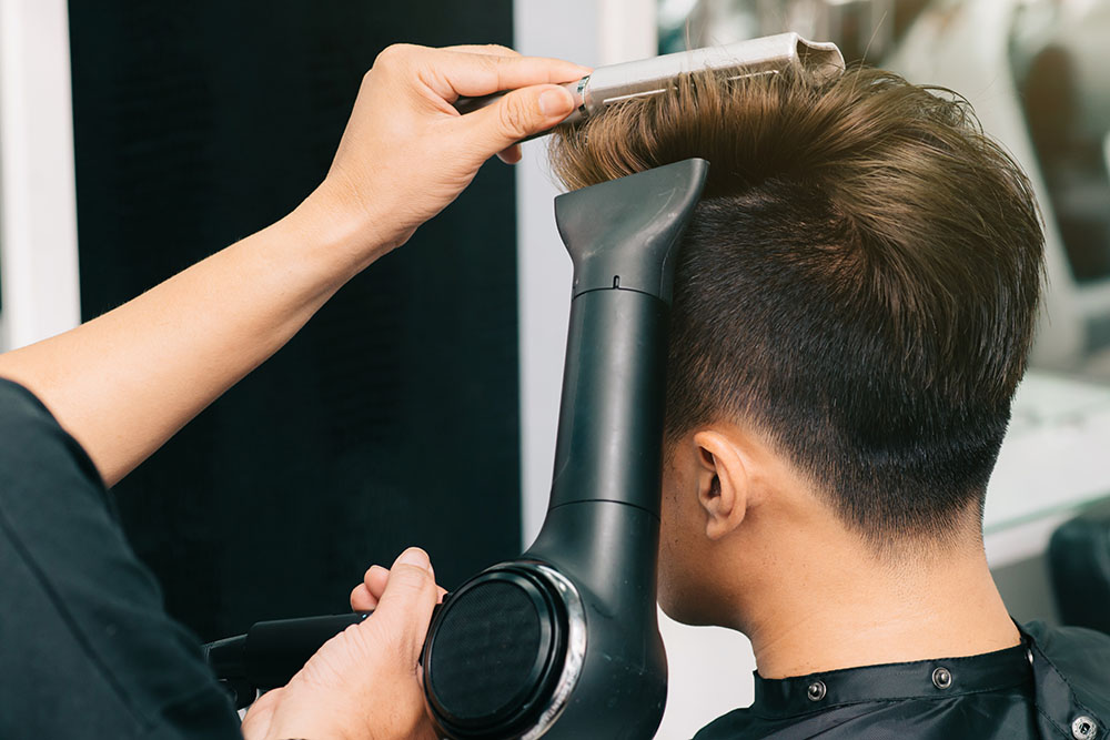 Eine Friseurin schneidet einem Mann die Haare